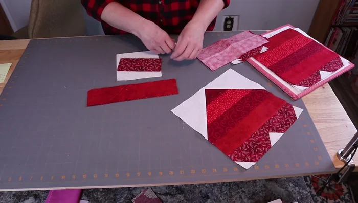 Prepare fabric pieces: Four 1.5-inch squares, two 5.5-inch background squares, four 2.5 x 10.5-inch strips, two 2.5 x 5.5-inch rectangles.