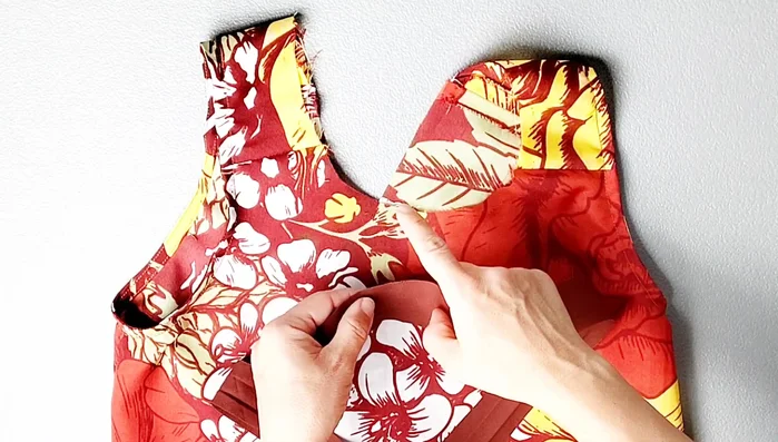 Attach neck binding: Place binding right sides together with bodice, matching notches. Pin, sew with 3/8 inch seam allowance. Clip into V seam allowance, trim, understitch, turn, pin, and edgestitch.