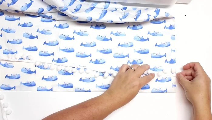 Attach pom-pom trim: Fold the trim over the edge and sew it along the top seam.