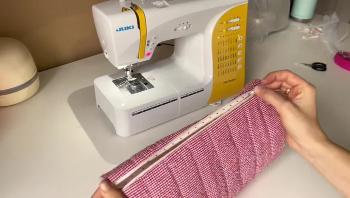 Sew the sides of the pouch together. Form a tube with the right sides of the fabric together, aligning the zipper in the middle. Sew close to the zipper, stretching the fabric slightly to avoid bunching. 