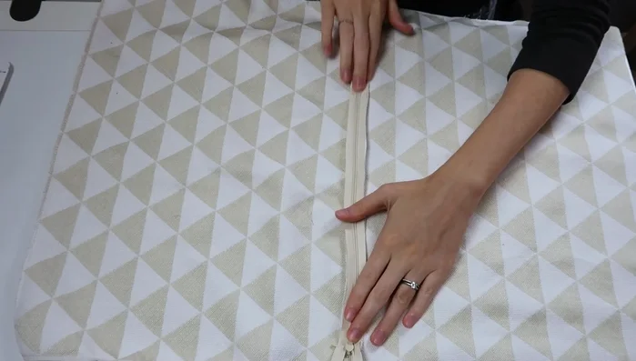 Prepare the zipper: Open the basted seam. Iron the zipper teeth away from the zipper tape on both sides. Place the zipper along the seam, matching the center of the zipper and the center of the seam. Pin and baste it down with contrasting thread.