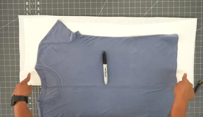 Prepare the T-shirt and paper: Fold your t-shirt in half and press the center crease. Fold a large sheet of paper in half. Place the folded t-shirt's crease along the paper's fold.