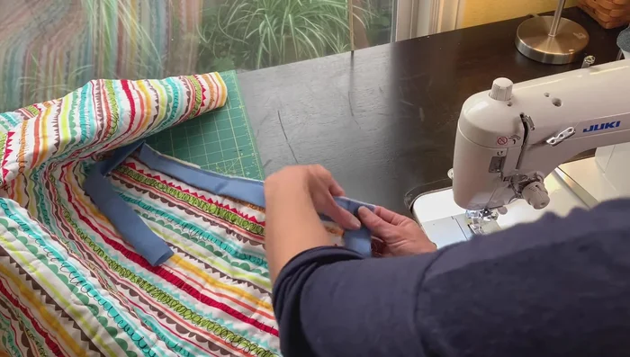 Finish the binding: Fold the binding over to the front, creating a clean edge. Top stitch around the quilt's perimeter, closing the opening. Mitre the corners neatly.