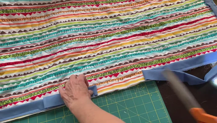 Join binding ends: Trim the tails of the binding to 2.5 inches. Place right sides together, pin, and sew along the edges to join the ends neatly. Trim excess fabric, ensuring the layers are flat before stitching.
