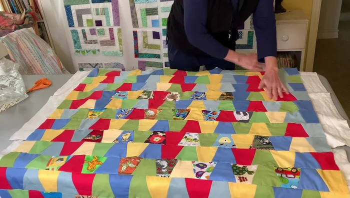 Create the quilt sandwich: Place the quilt top on the batting, then add the backing fabric. Use a fusible batting for easier handling. Press the layers together, starting from the center and working outwards.