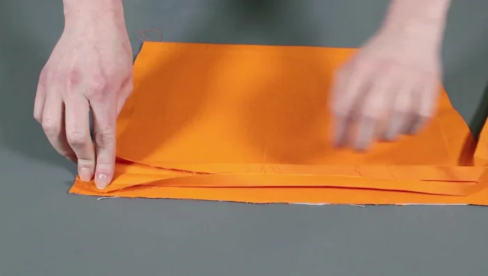 Attach bias tape to pockets: Fold tape in half, press, and sew to back of pocket pieces along the half-crease.