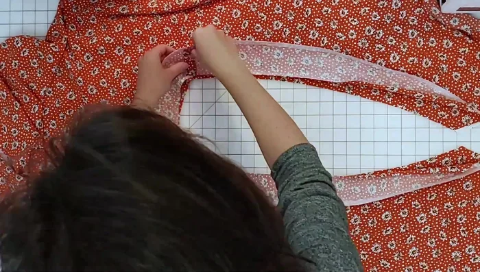 Attach the facings to the neckline and wrap edge, sew with 3/8 inch seam allowance. Trim seam allowance in half, press facing away from bodice, and understitch.