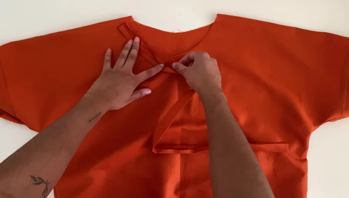 Attach the neckline binding: Open the bias binding, pin it along the entire neckline with right sides facing. Sew, trim excess binding, sew the ends together to form a circle, and then sew along the fold of the binding. Fold the binding over and pin along the neckline, then sew to finish the edge.