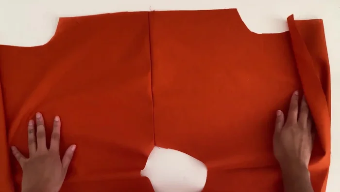 Attach the sleeve cuffs: Open the sleeve cuff pieces, fold in half with wrong sides facing, align with the armhole, and pin. Sew along the edge using a 3/8 inch or 1 cm seam allowance. Overlock the seams and press the cuffs to the right side.