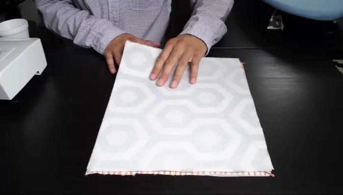 Construct the bag flap: Sew the main and lining fabric pieces together, creating rounded corners and a V-shape cut at the bottom corners. Turn right side out and iron.