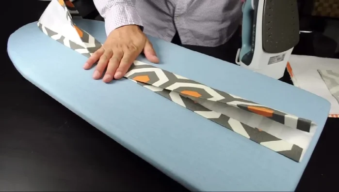 Construct the bag strap: Sew together strap pieces and strap tabs. Attach D-rings and fold strap into D-rings. Attach strap tabs to the top of the bag using zigzag stitch and bar tacks.