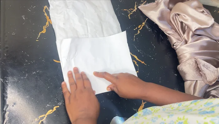 Fold the fabric in half lengthwise, then in half again to create a large triangle. This allows you to cut the front and back of the skirt simultaneously.