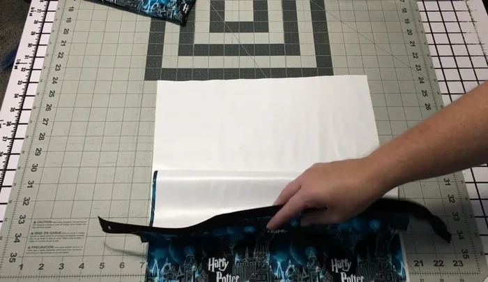 Prepare the back panel: Lay PUL (shiny side up) and outer fabric (print facing you, right side to right side). Ensure the print matches the front panel; flipping the outer fabric upside down might be necessary to achieve this.