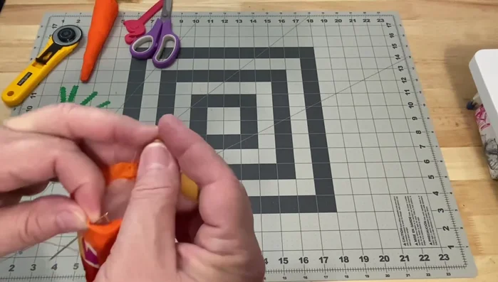 Close the top: Fold down the top edge of the carrot and hand-stitch it closed using a running stitch. Secure the stitching with a knot.