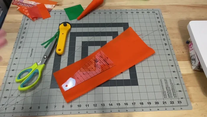 Cut carrot shapes: Place your Dresden ruler on the folded fabric and cut out two carrot shapes per carrot. You can adjust the size by using different inch marks on the ruler.