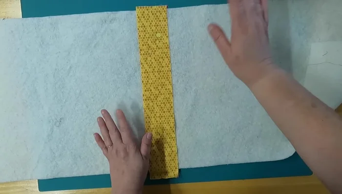 Stitch the center strips: Stitch along both sides of the center strips to secure them to the batting. Use neutral thread that complements both fabric sides.