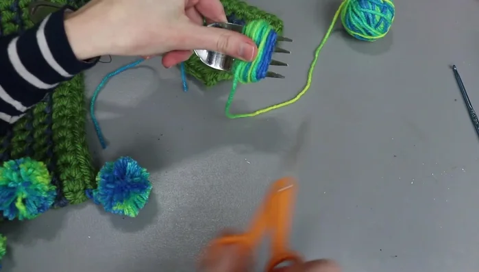 Slide the wrapped yarn off the fork, pull the knot tight, and tie a second knot.