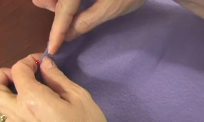 Start the blanket stitch. Begin the blanket stitch, hiding the knot inside the fabric. Make consistent ¼-inch stitches.