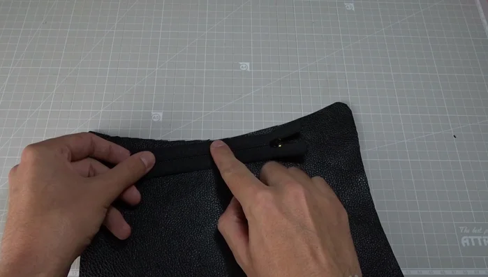 Sew the zipper to the first leather piece from the bottom stop to the top stop, using long stitches and a zipper foot. Remember to backstitch at the beginning and end. Lower the needle and raise the presser foot to open the zipper halfway for easier sewing.