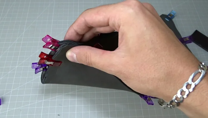 Position straps between leather pieces, ensuring they're centered and visible only at the ends. Sew around the pillow again, carefully managing the thickness of the materials and making notches to reduce bulk.