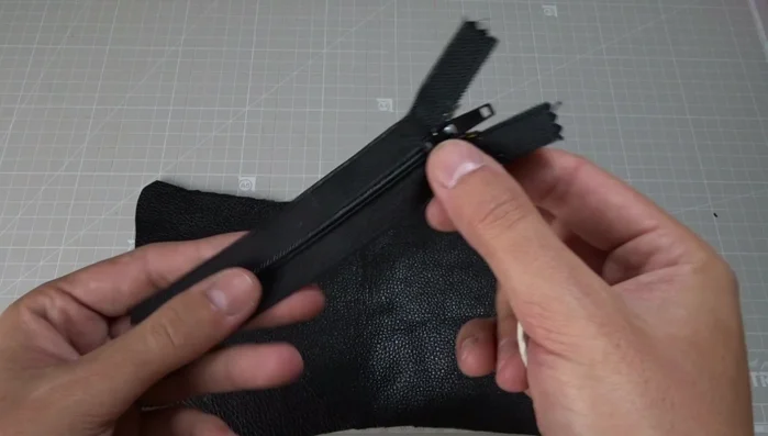 Sew the zipper to the first leather piece from the bottom stop to the top stop, using long stitches and a zipper foot. Remember to backstitch at the beginning and end. Lower the needle and raise the presser foot to open the zipper halfway for easier sewing.