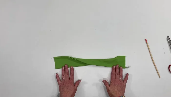 Twist one end and fold in half, aligning edges. Pin.