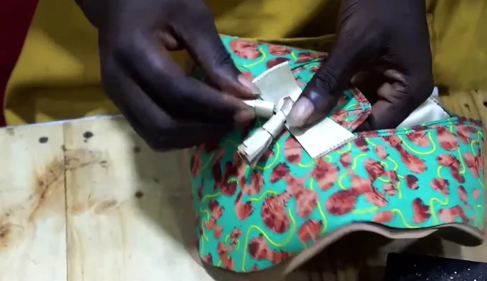The final step is to ensure the fabric is neatly wrapped around the tassel and firmly attached. The video shows a finishing step where the edges are secured. 