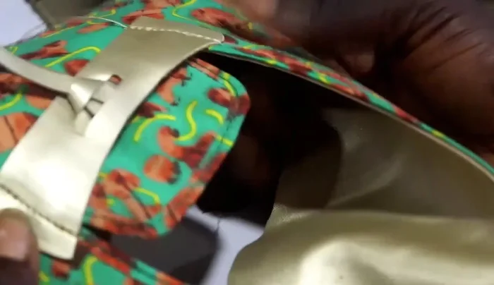 Secure the fabric to the tassel using glue (likely fabric glue). The video shows a process of wrapping and gluing, but specifics on glue type and application aren't detailed. 