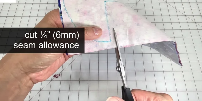 Trim seam allowance: Cut all around leaving a quarter inch seam allowance. Cut into inner corners, and trim outer corners at an angle. Trim away half of the seam allowance along outer curves for less bulk. Make notches into the inner curve.