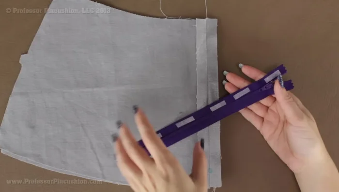 Baste the zipper tape to the fabric using a zipper foot on your machine. Use a basting stitch. To avoid sewing over the zipper pull, temporarily lift the presser foot, zip up past the pull, then continue sewing.