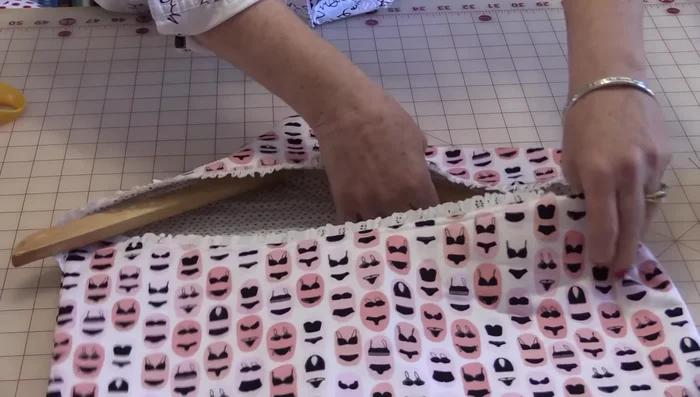 Insert the hanger through the opening. The hanger should be underneath both flaps.