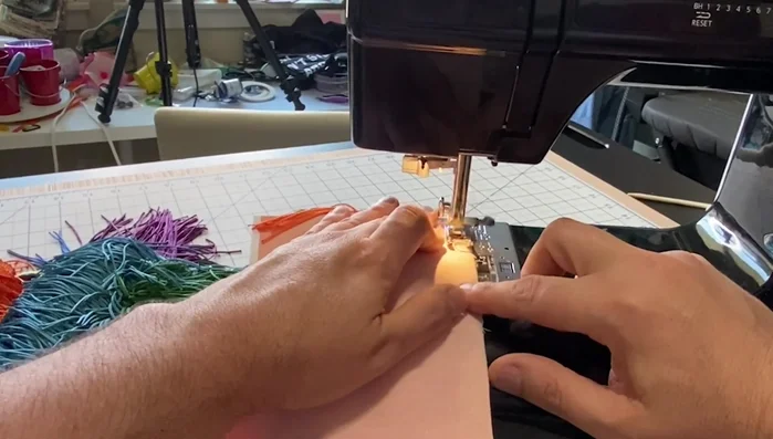 Sew a straight stitch along the raw edge of the fabric at a 1/2 inch seam allowance to encase the fringe.