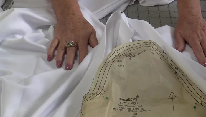 Ease and distribute fabric: Gently pull basting threads to ease the sleeve's fullness, ensuring even distribution of fabric between pins. Work in sections to maintain an even fit.