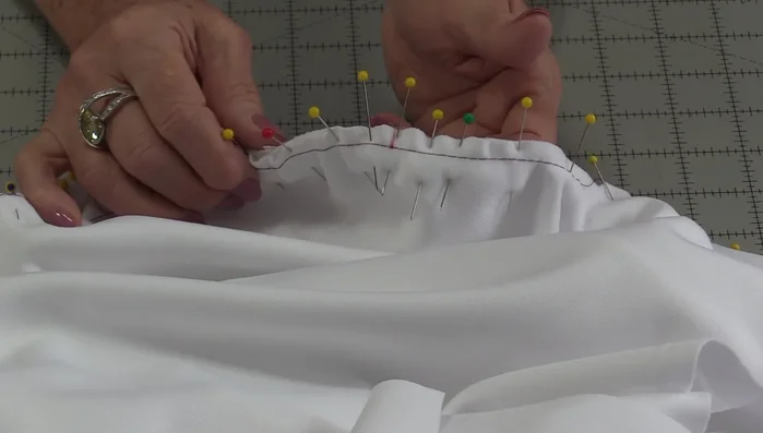 Baste sleeve to garment: Once evenly distributed, baste the sleeve to the garment to secure the fabric and ensure a smooth seam.