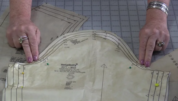 Pin sleeve to garment: Place garment right-side up, align notches and dots, ensuring correct sleeve placement. Pin, leaving tails of basting threads.