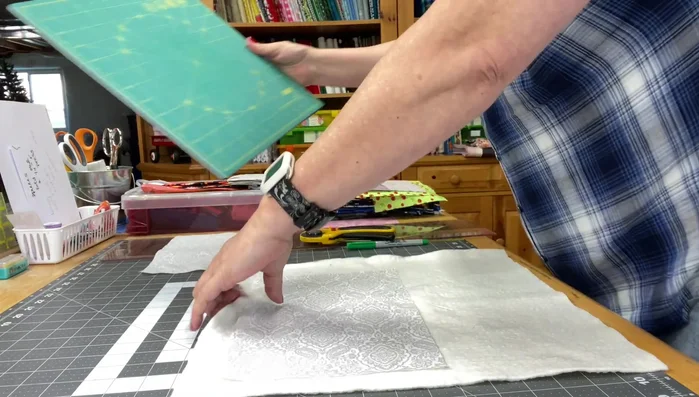 Layer one fabric piece (right side up) over batting, then layer the pocket pieces (right side up) on top. Pin in place. Mark 0.5-inch and 3.5-inch points for stitching pockets.