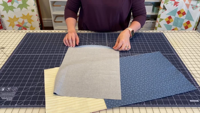 Hem one short edge of each backing piece by pressing under ¼ inch, folding again, pressing, and sewing a seam.