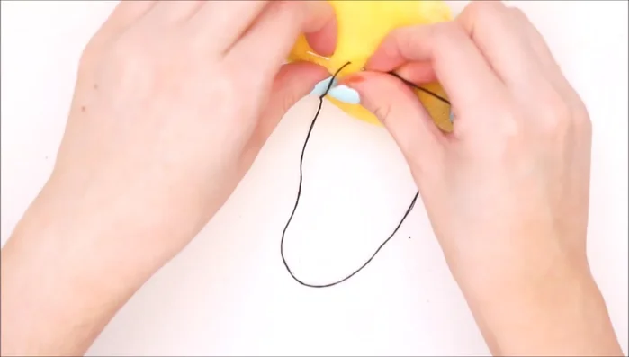 Embroider a sad-faced mouth using black thread.