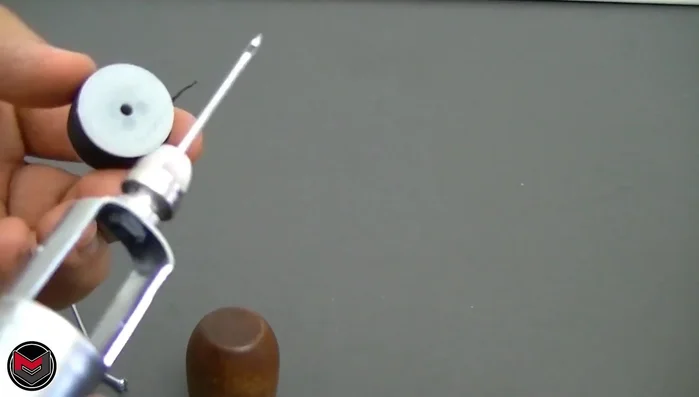 Feed the threaded needle through a small hole near the nut of the sewing awl. (Note: The smaller hole on the awl is not used in this method)