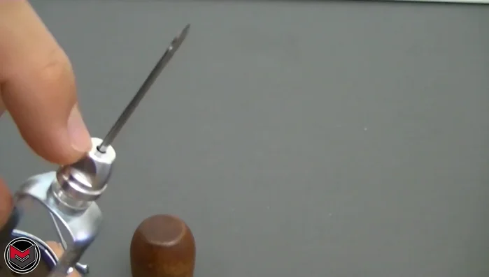 Feed the threaded needle through a small hole near the nut of the sewing awl. (Note: The smaller hole on the awl is not used in this method)