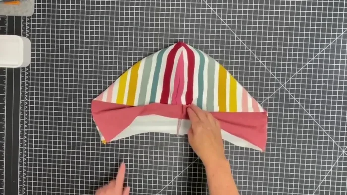 Assemble the hood: Bring the hood pieces wrong sides together, pin bottom edges, and baste with a zigzag stitch, matching notches, seams, and shoulder marks. Mark a top stitch line 2.5 cm (1 inch) from the edge and top stitch.