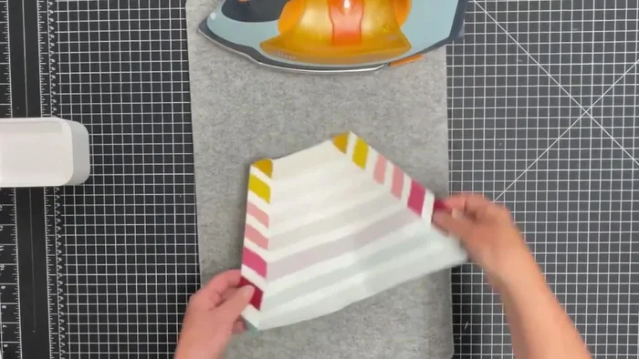 Prepare the kangaroo pocket: Fold the long angled edges to the wrong side, press, and finish the raw edges. Fold back into position and top stitch.