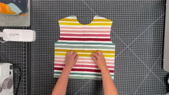 Attach the pocket: Pin the wrong side of the pocket to the right side of the front, matching centers. Edge stitch along the top, sides, and bottom.