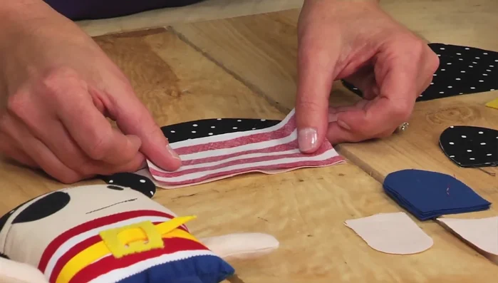 Sew the shirt and body: Pin the shirt fabric to the doll's face (right sides facing) and sew along the edges. Repeat with the back piece to attach the hat.