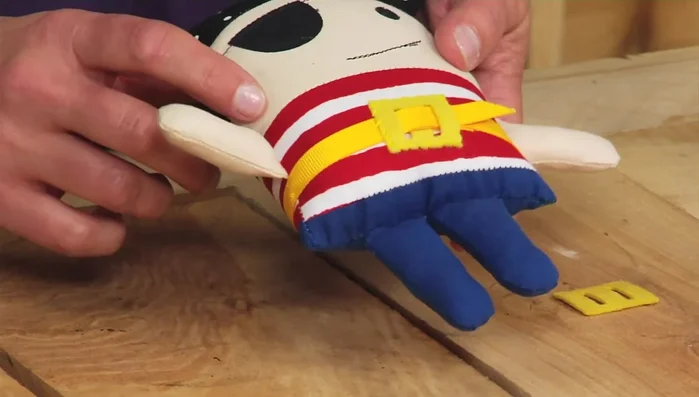 Attach the belt buckle: Thread a ribbon through the belt buckle and hand-stitch it to the doll.