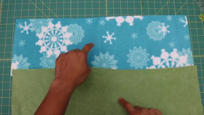 Cut fleece fabric to desired dimensions. Adult size: 8 inches tall x 25 inches long; Child size: 7 inches tall x 22 inches long. Ensure the length is along the stretchy crosswise grain.