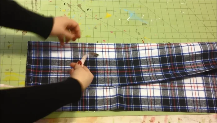 Sew a straight stitch along the pinned line to secure the scarf and fringe.