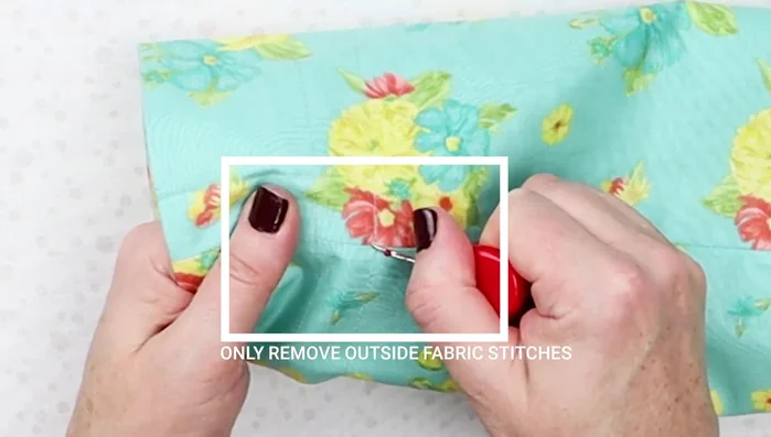 Remove Drawstring Channel Stitches: Carefully remove the stitches in the outer fabric between the two channel lines using a seam ripper.