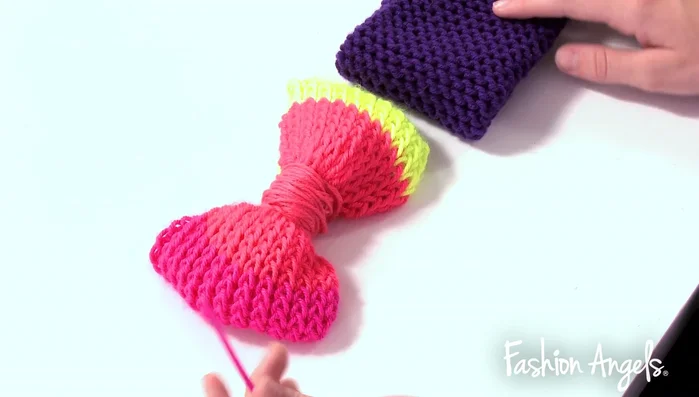 Attach the bow to the headband using the excess coral yarn and needle.