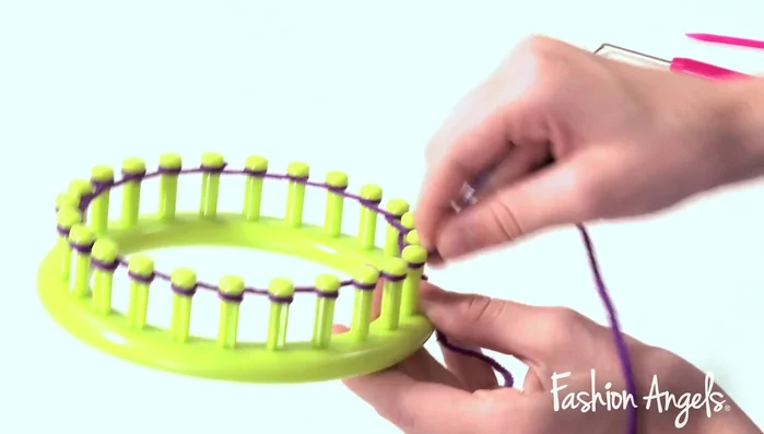 Continue wrapping purple yarn around the loom pegs, completing the second row.